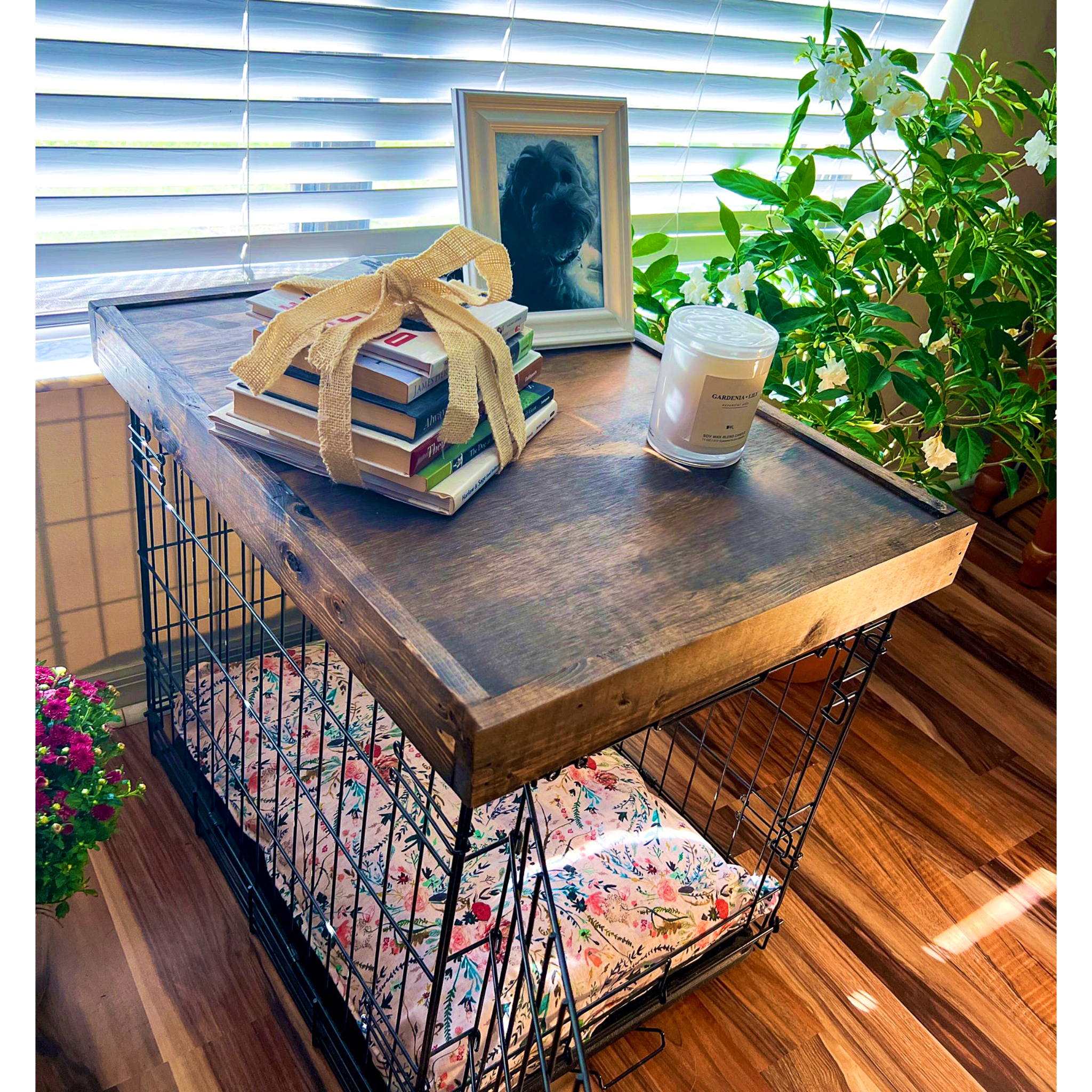 Wooden crate with a wooden top, books, a candle, and a plant on a wooden floor. wooden crate topper, wooden kennel topper, dog crate table, dog kennel table, dog crate cover, dog crate furniture, dog crate end table, dog kennel furniture, dog bed furniture, wooden dog furniture, wood table dog crate, wooden dog kennel furniture, pet furniture wood pet furniture