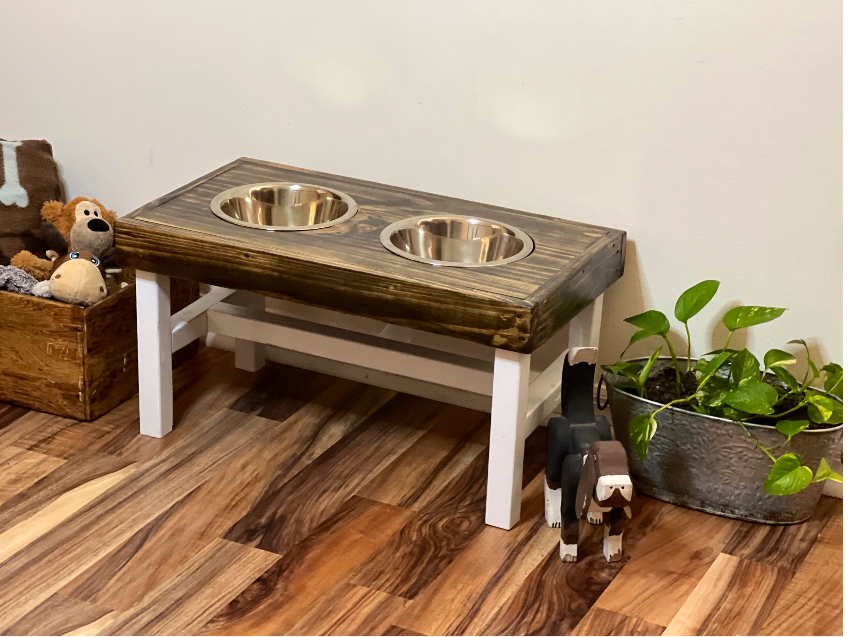 Wooden pet feeding station with two bowls on a wooden floor. Raised dog bowl stand, dog bowl holder, large dog bowl stand, small dog bowl stand, wooden dog bowl stand raised, elevated pet bowl stand, elevated dog bowl stand, dog bowl stand wood,